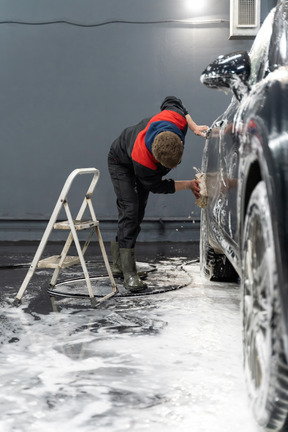 Junger mann, der auto wäscht