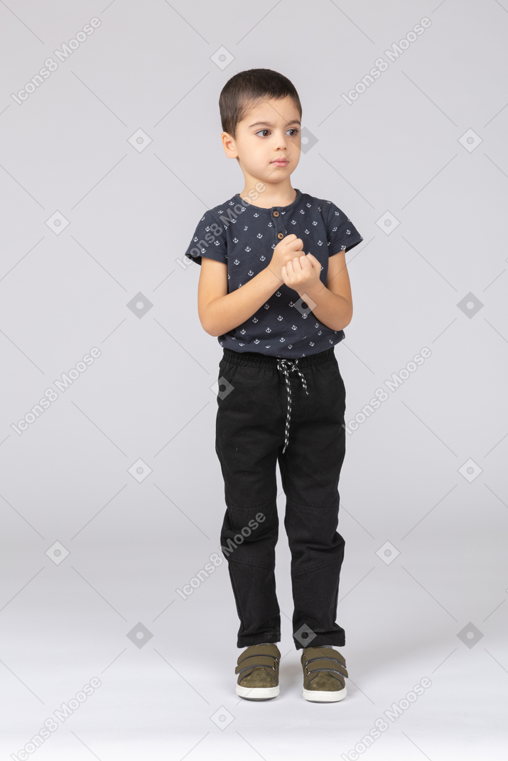 Вид спереди серьезного мальчика в повседневной одежде, смотрящего на что-то