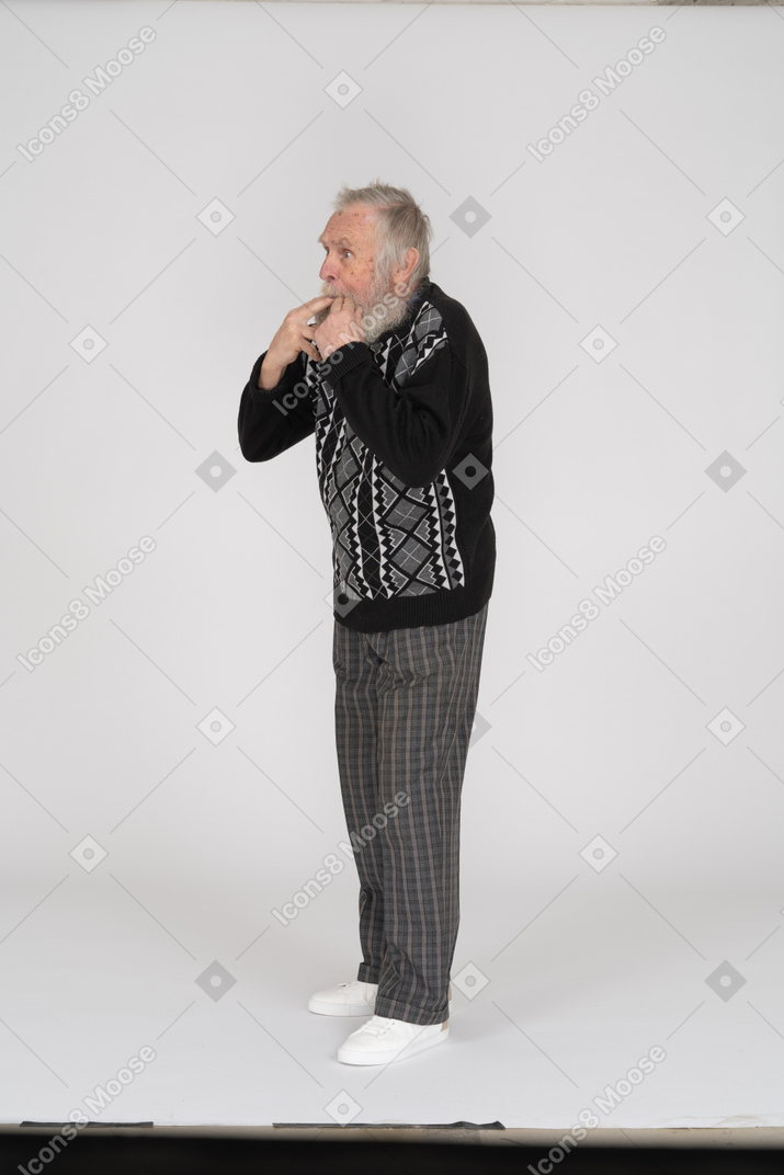 Side view of old man whistling with fingers