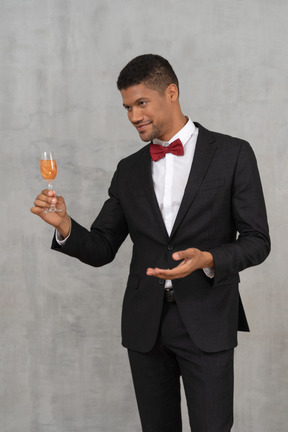 Молодой человек держит бокал шампанского и смотрит в сторону