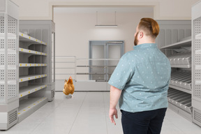 Man standing in an empty grocery isle looking at rooster