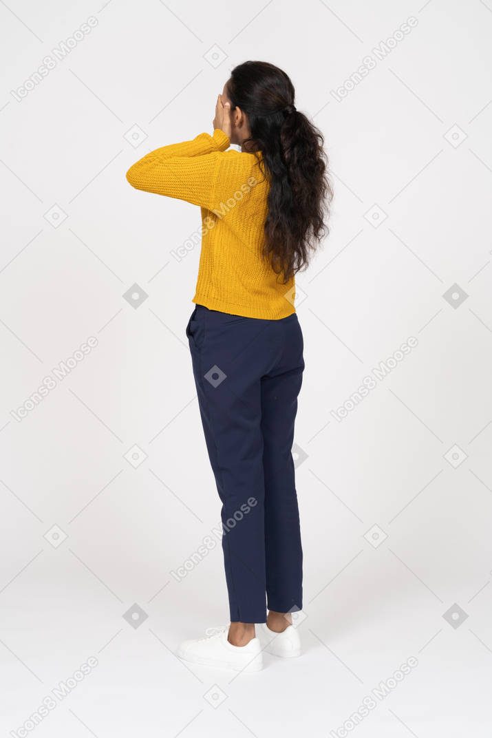 Rear view of a girl in casual clothes covering face with hands