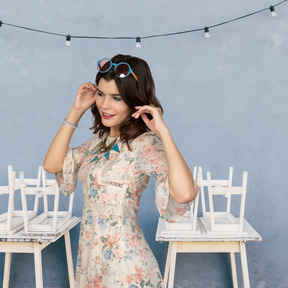 Woman in floral dress standing between two tables