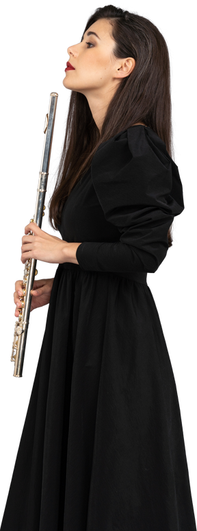 Vista lateral de uma jovem séria de vestido preto segurando uma flauta