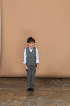 Vista frontal de un niño feliz en traje mirando a la cámara