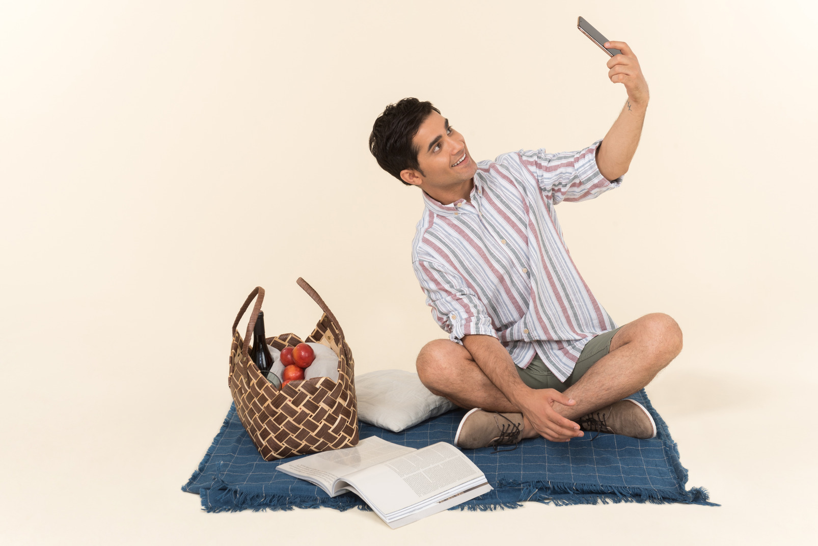 Young caucasian guy sitting on blanket and making a selfie