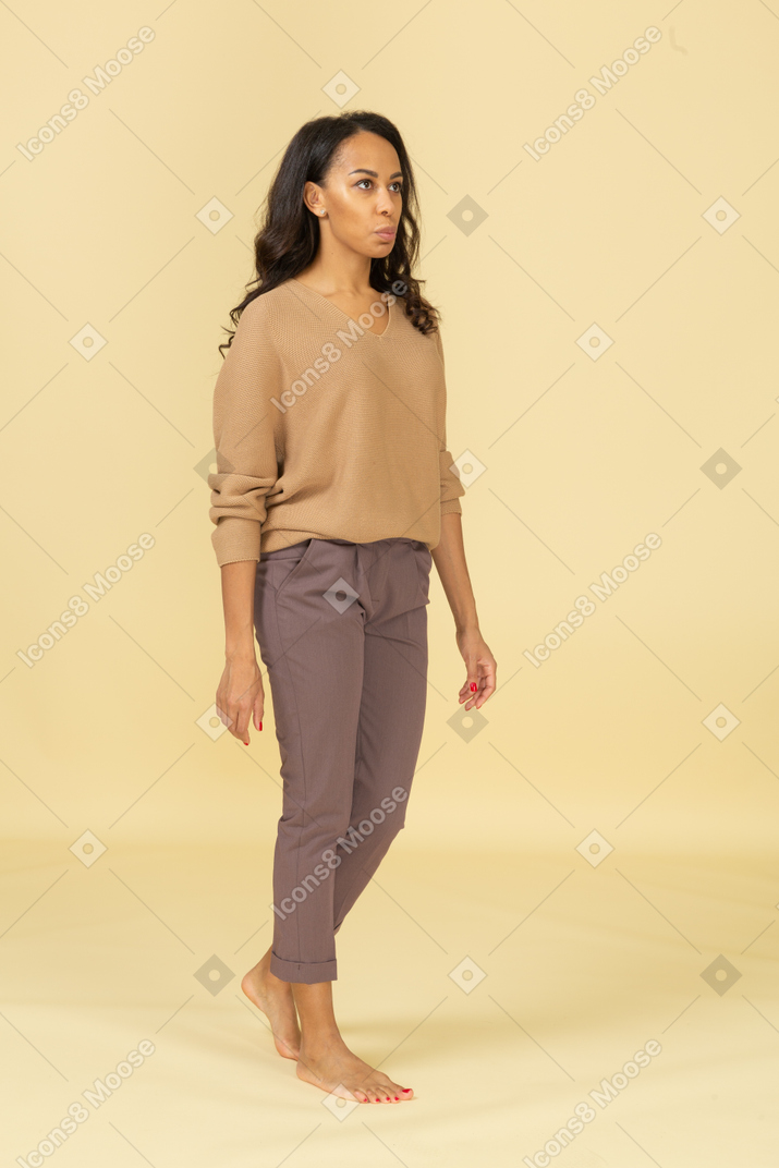 Vista de tres cuartos de una mujer joven en ropa casual caminando