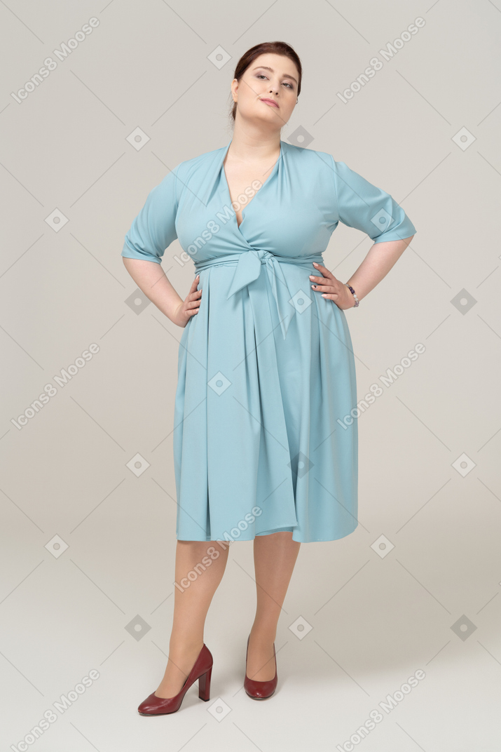 엉덩이에 손을 대고 포즈를 취하는 파란 드레스를 입은 여성의 전면 모습