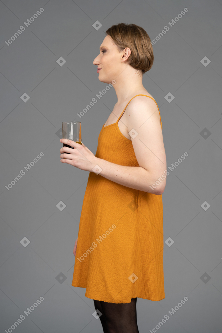 手拿玻璃的橙色连衣裙的人的侧视图