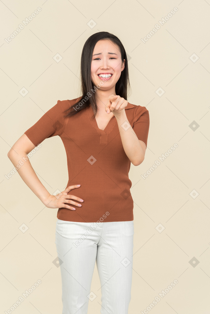Smiling young asian woman pointing forward
