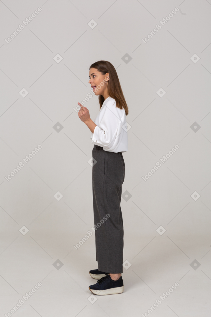 Вид сбоку предупреждающей молодой леди в офисной одежде, поднимающей палец
