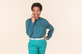 Black woman with a short haircut, wearing all blue, standing against a plain pastel background, looking emotional