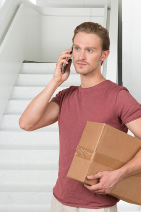 A man holding a box and talking on a cell phone