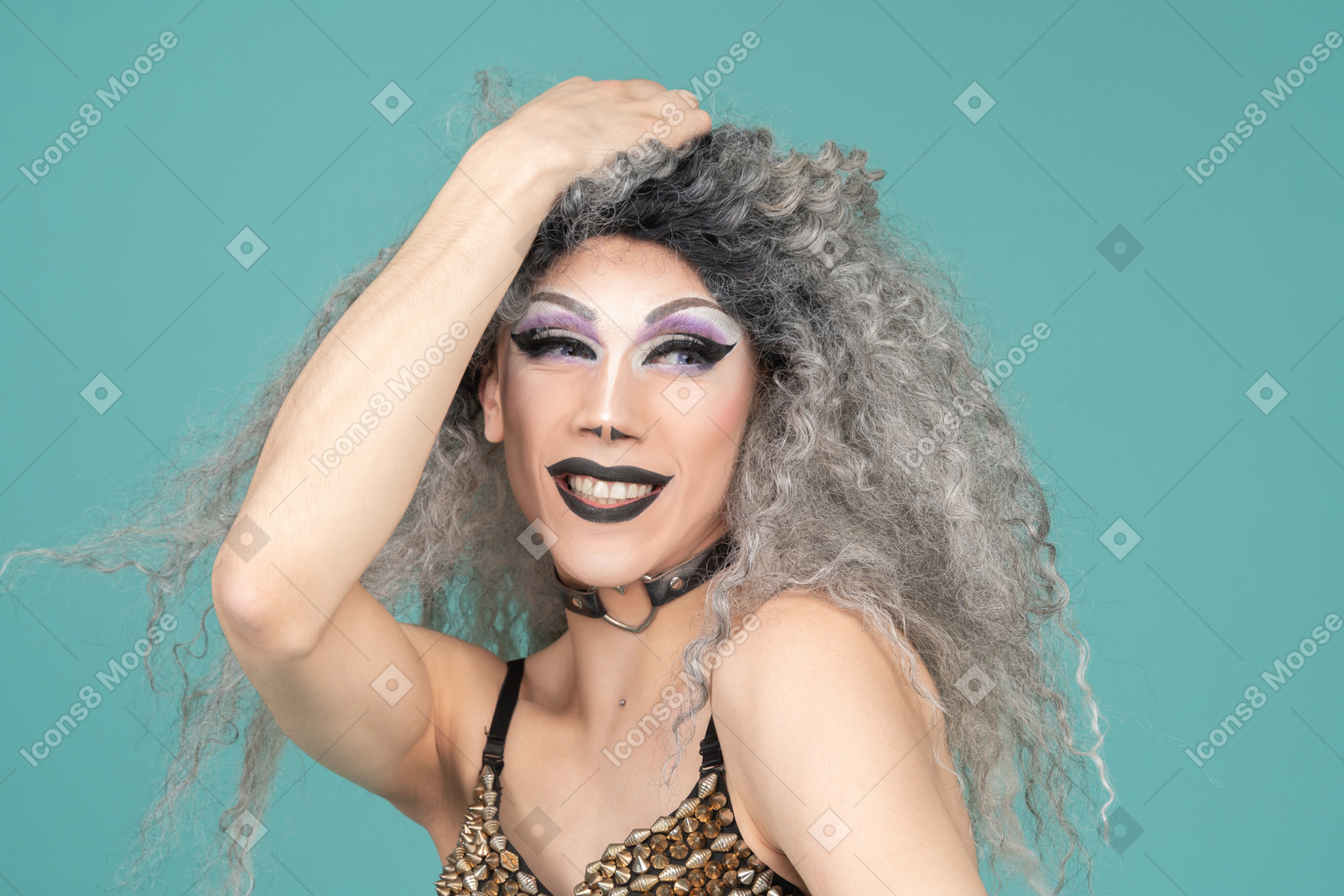 Headshot of a drag queen smiling with hand on top of head