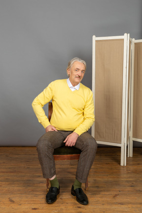 Homme souriant assis sur une chaise et regardant la caméra