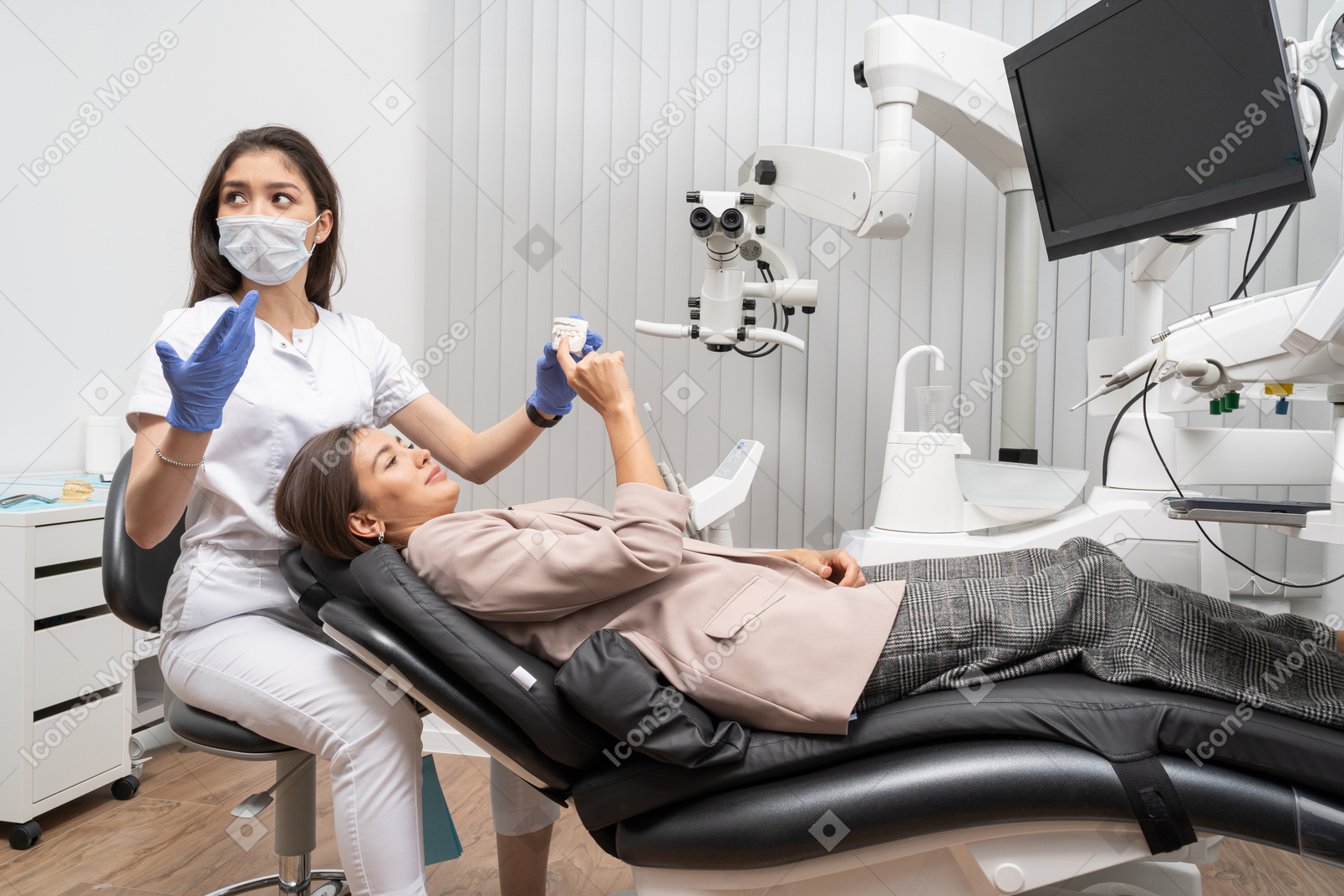 Full-length of a perplexed female dentist showing her female patient a teeth model
