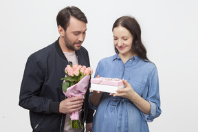 Мужчина дарит жене подарок и цветы