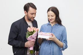 Homem apresentando presente e flores para sua esposa