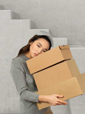 Tired woman carrying boxes