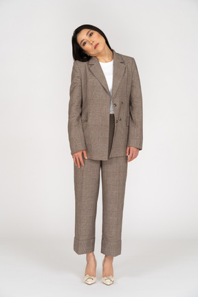 頭を傾ける茶色のビジネススーツの若い女性の正面図