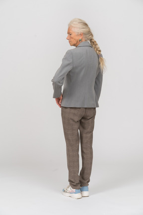 一个穿着西装、手放在臀部的老妇人的后视图