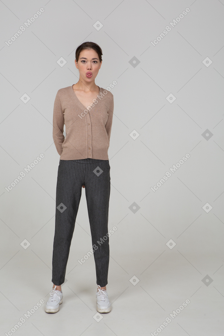 Front view of a young lady in pullover and pants showing tongue