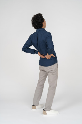 Rear view of a man in casual clothes suffering from pain in lower back