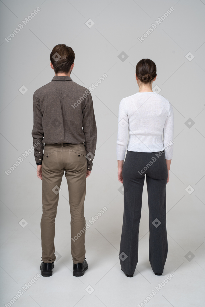 静止しているオフィスの服を着た認識できない若いカップルの背面図