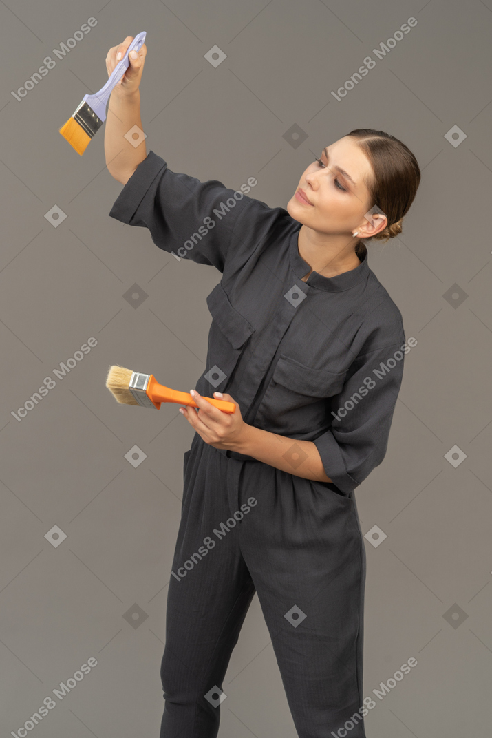 페인트 브러시를 선택하는 회색 작업복을 입은 여성