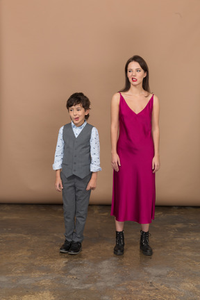Вид спереди улыбающегося мальчика и женщины в красном платье