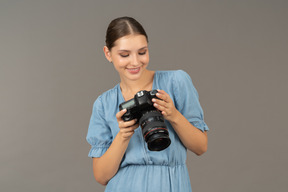 Front view of a smiling young woman in blue checking pictures