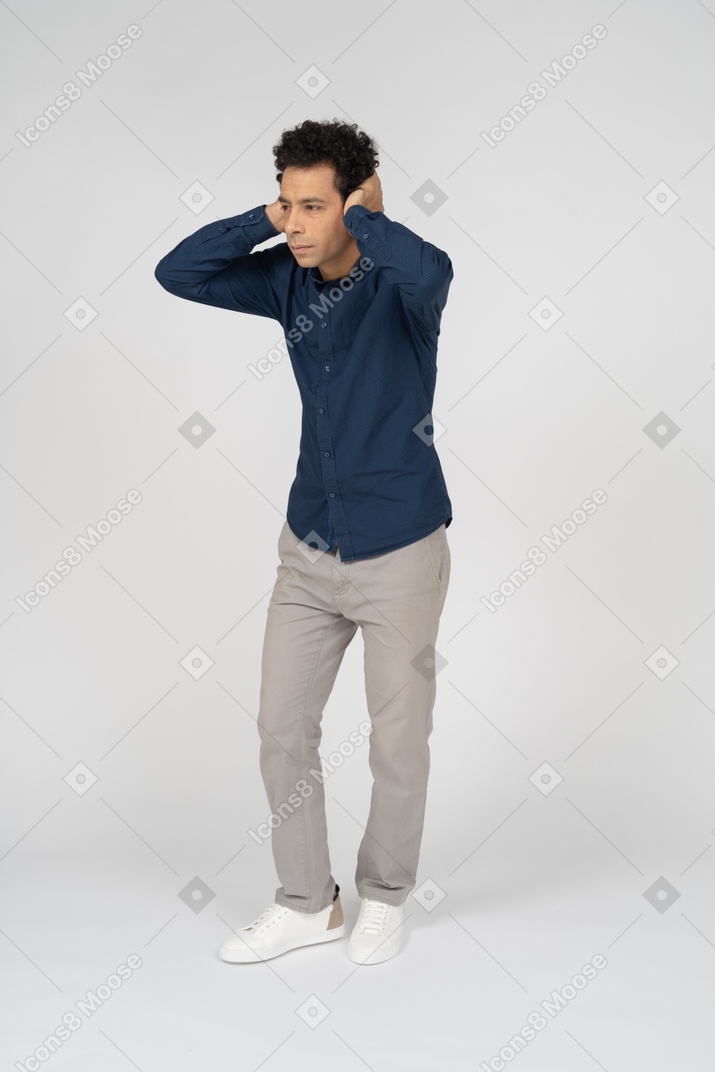 Vista frontale di un uomo in abiti casual che copre le orecchie con le mani
