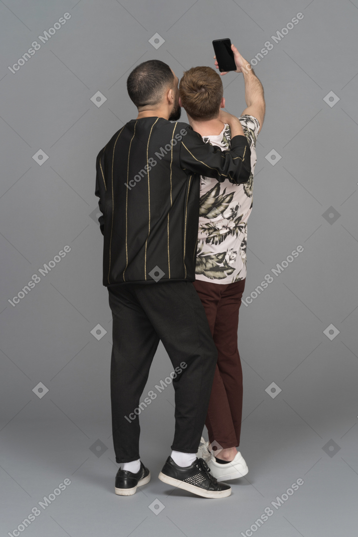 Back view of two young men taking a selfie