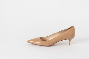 A side shot of a beige lacquer court shoe