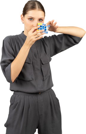 Front view of young woman in a jumpsuit holding the rubik's cube