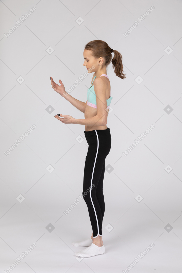 Side view of a teen girl in sportswear raising hands