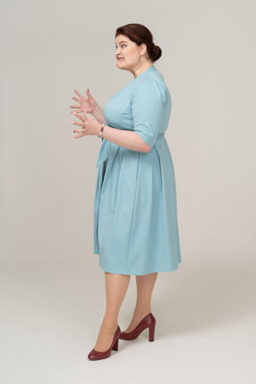 Vista lateral de uma mulher zangada em um vestido azul gesticulando