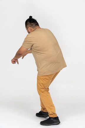 Plus size asian man stooping down with outstretched hand