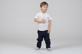 Little boy standing with hand on chest