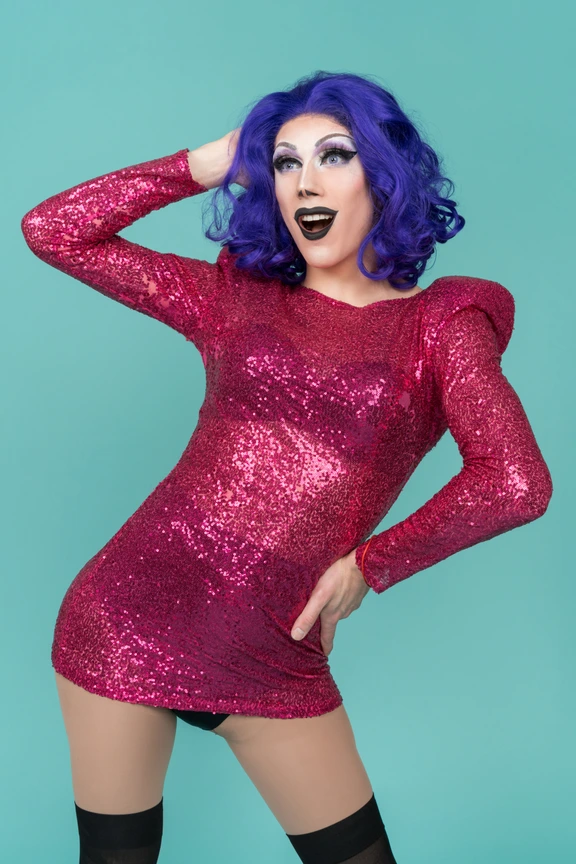 Drag queen in pink sequin dress having a drink from plastic cup Photo