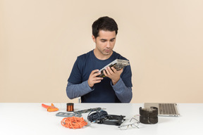 A young man in casual blue clothes working with computer details