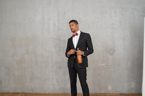 Man in suit and bow tie standing with a bottle in his hand