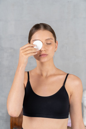 Front view of a young woman removing eye makeup