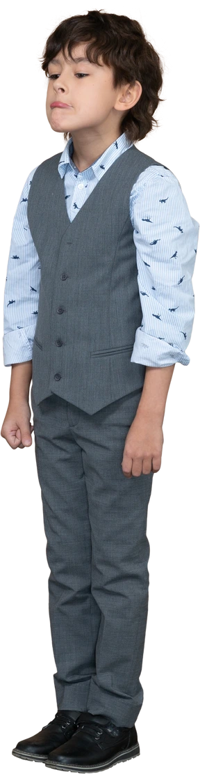 Front view of a boy in suit standing still and making faces