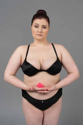 Body positive woman in black lingerie holding pink menstrual cup