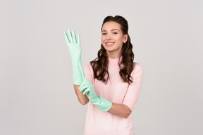 Attractive young woman putting on cleaning gloves