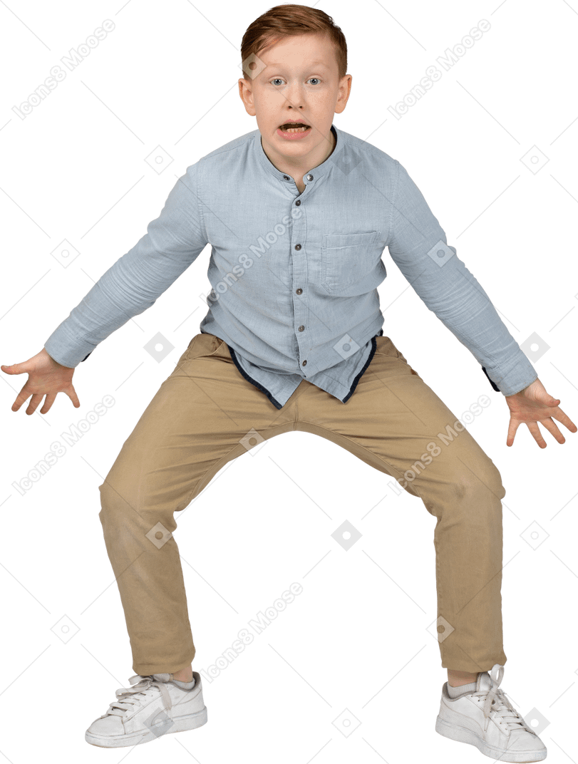 Front view of a boy squatting with outstretched arms and looking at camera