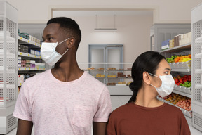 A man and a woman wearing face masks in a grocery store