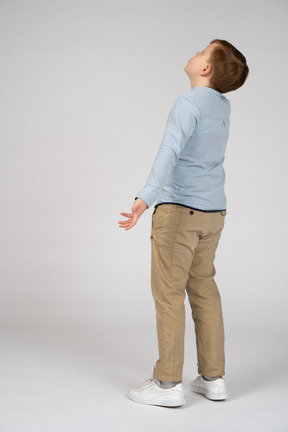 Vista de tres cuartos de un niño con ropa informal mirando hacia arriba