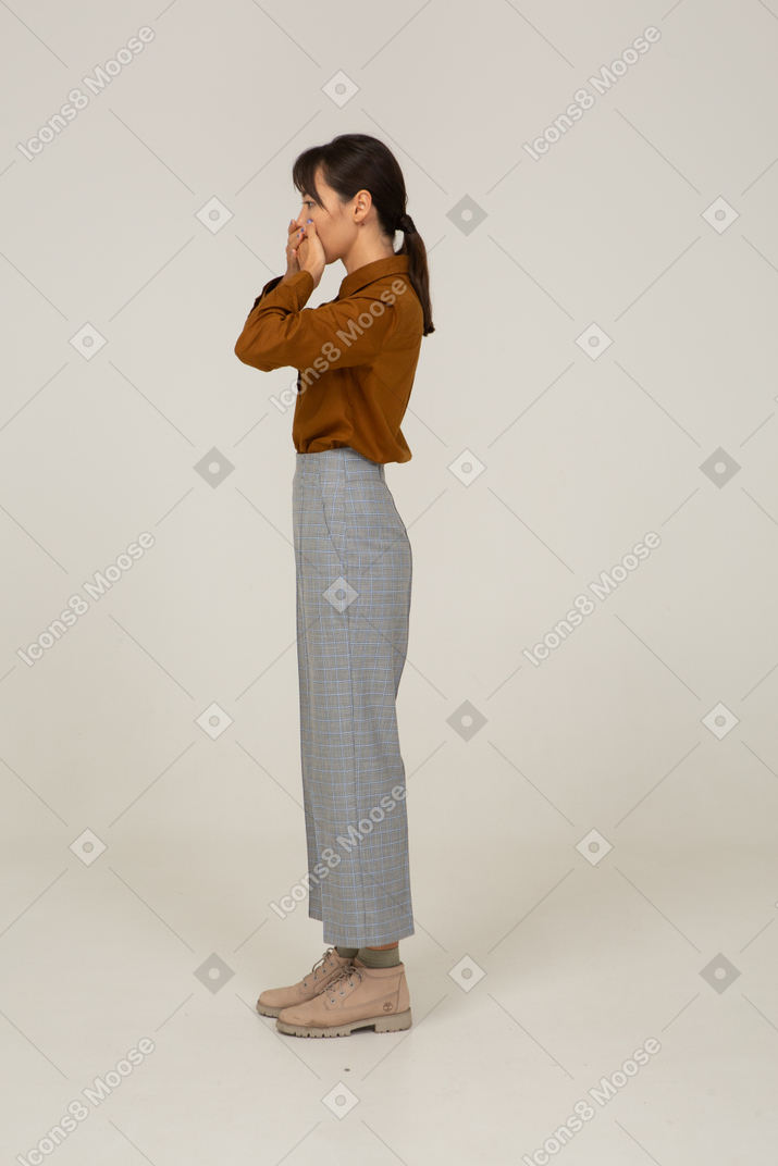 Side view of a young asian female in breeches and blouse touching her face